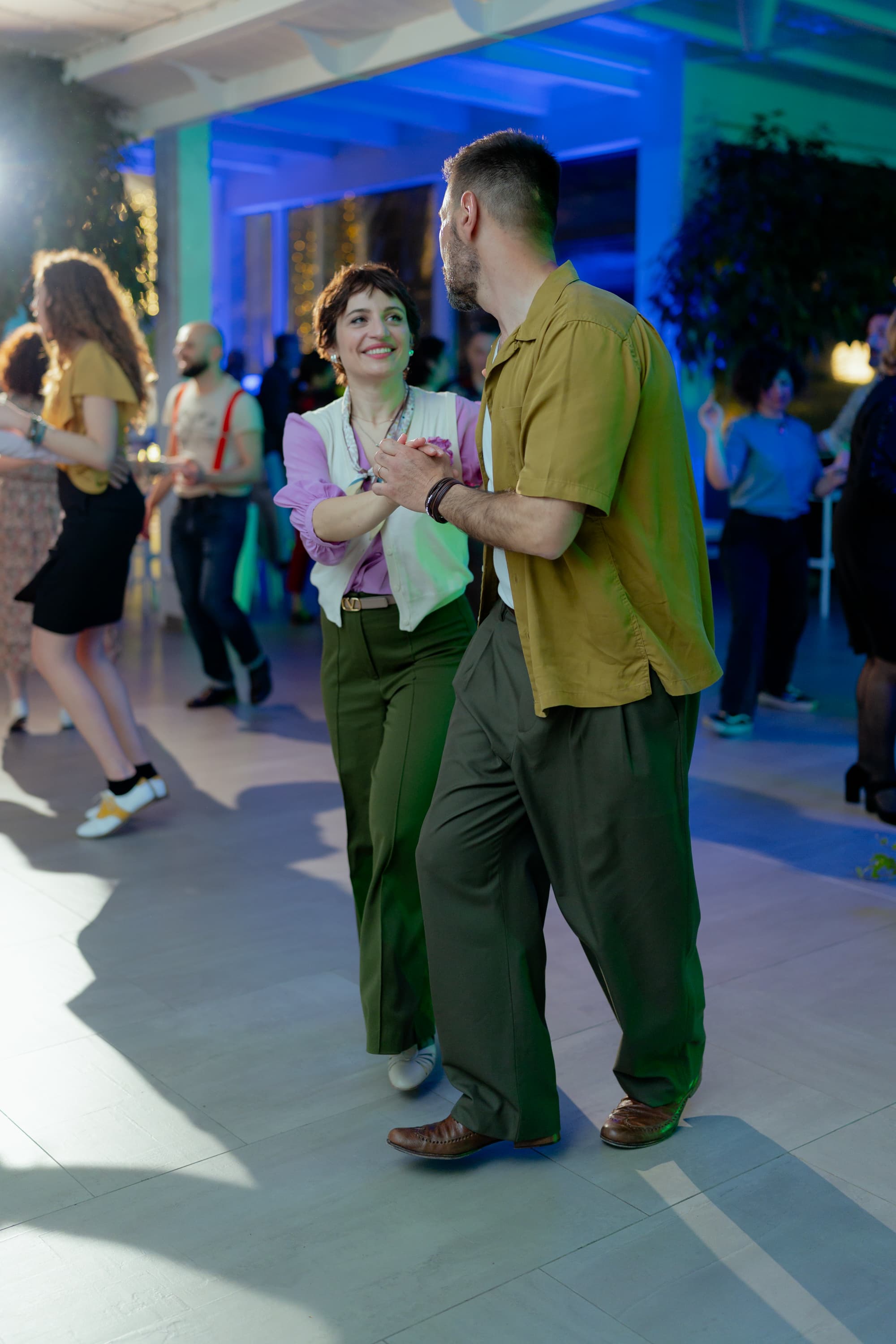 Due ballerini di Lindy Hop a metà di uno swing out, sorridenti, su una pista da ballo
